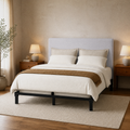 Angle | Three-quarter bedroom view showing the upholstered headboard, black bed frame, bedding, walnut nightstands, and lamps