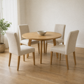 In a room | all four matching chairs at a warm oak dining room's round table, soft morning sidelight from the left