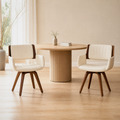 In a room | the pair beside a round table in a warm flax dining room, bright midday light
