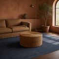 Terracotta room | woven rattan coffee table in front of a caramel sofa on a plain indigo rug