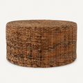 Front | round natural-brown woven rattan drum coffee table on a warm white studio background