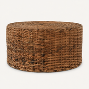 Front | round natural-brown woven rattan drum coffee table on a warm white studio background
