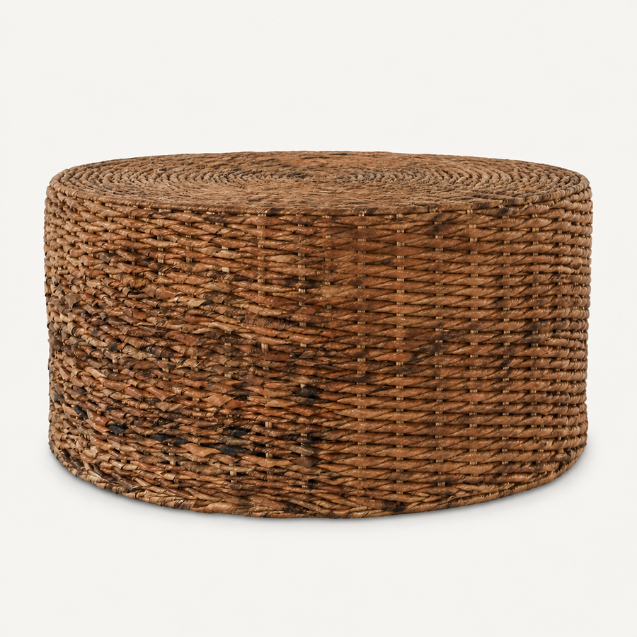 Front | round natural-brown woven rattan drum coffee table on a warm white studio background