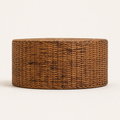 Side profile | low round woven rattan coffee table from tabletop height on a warm white studio background