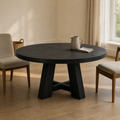 In a room | round black trestle dining table in a plaster dining room, low golden afternoon light from the right