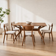 In a room | walnut trestle table and all four light-beige chairs, window light at left