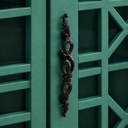 Hardware macro | ornate dark metal pull mounted on a teal-green lattice door