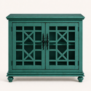 Front studio | antique teal-green cabinet with two closed geometric lattice doors, dark ornate pulls, molded top and four turned bun feet