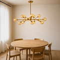 In a room | 15-globe amber and gold sputnik chandelier hanging over a round oak dining table, morning light
