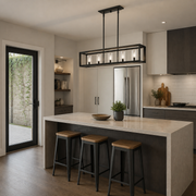 Scale | Matte black five-light linear chandelier above a kitchen island beside a full-height door