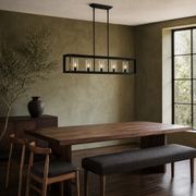 Room 2 | Matte black five-light linear chandelier above a walnut dining table in an olive room