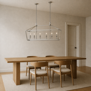 Scale | polished chrome 6-light linear chandelier above a dining table beside a full-height doorway for scale