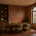 In a room | polished chrome 6-light linear chandelier over a dark dining table in a terracotta library room