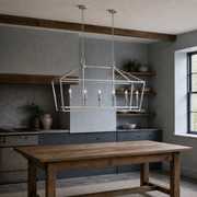 In a room | polished chrome 6-light linear chandelier over an oak work table in a cool blue-gray beamed kitchen