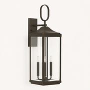 Three-quarter | Antique bronze wall lantern showing the clear glass cage and rectangular wall backplate