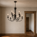 Scale | dark bronze nine-light chandelier beside a full-height wood-trimmed doorway