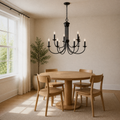 Angle | dark bronze nine-light chandelier from a corner view over a round pale oak dining table