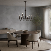 In a room | dark bronze nine-light chandelier over a round dark wood table in a cool limewash dining room