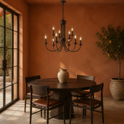 In a room | dark bronze nine-light chandelier over a round dark oak table in a terracotta room with garden doors
