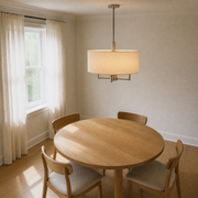Dining room | elevated second angle of the off-white linen-blend drum chandelier over a round pale-oak table