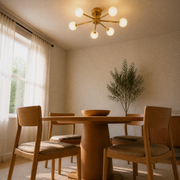 Angle | brushed brass six-globe semi-flush fixture from a low corner angle in a warm dining room