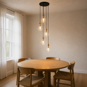 In a room | five clear glass pendants cascading over a round oak dining table