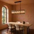 In a room | matte-black rectangular pendant glowing over a travertine dining table in a terracotta room