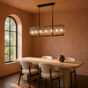 In a room | matte-black rectangular pendant glowing over a travertine dining table in a terracotta room