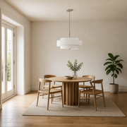 Scale in a dining room | off-white three-drum chandelier above a round table beside a full-height doorway