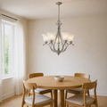 Dining room | brushed nickel five-light chandelier with five frosted bell shades over a round oak table by a left window