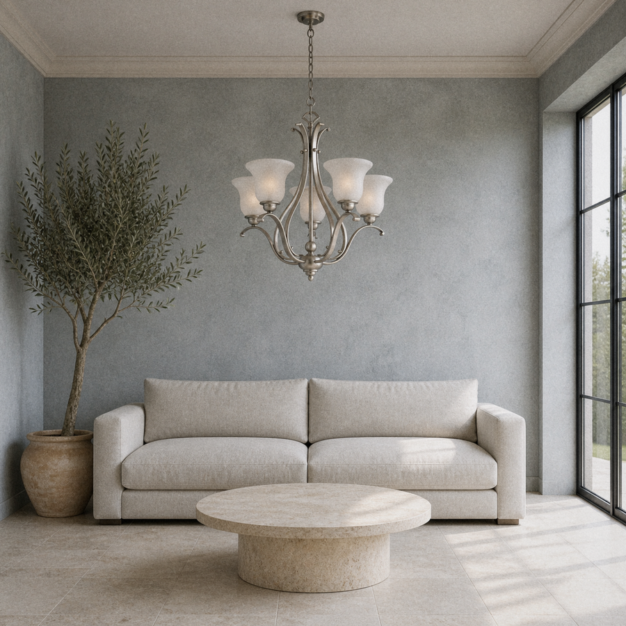 Cool living room | brushed nickel five-light chandelier above a low round stone table in a gray limewash room with tall windows