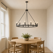 In a room | matte-black 12-light wagon-wheel chandelier hanging over a round oak dining table