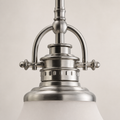 Hardware close-up | brushed nickel arched yoke, round finials, stepped collar, and top edge of the frosted glass shade