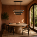 Terracotta garden dining room view | black three-tier rectangular LED chandelier above a round travertine table