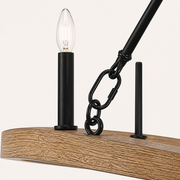 Hardware detail | black candle socket, clear candle bulb, black brace, and chain links over the light woodgrain ring
