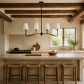 Kitchen | black four-arm pendant with white shades above a pale-stone island in a beamed kitchen