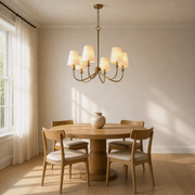 Dining room | six-light warm brass chandelier with six ivory linen shades over a round oak table