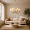 Living room | six-light warm brass chandelier with six ivory linen shades above a travertine table