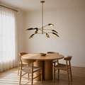 Dining room | eight matte-black cone shades with light-gold interiors on four brass arms over a round oak table