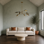 Living room | black-and-gold eight-light branch chandelier above a round travertine table