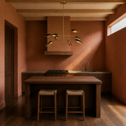 Kitchen | black-and-gold eight-light chandelier above a dark walnut island in a terracotta room