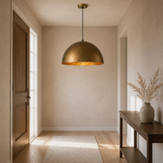 Entryway | hammered gold dome pendant hanging from the ceiling above a console
