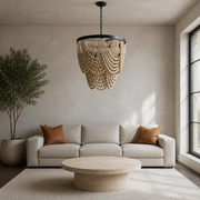 In a room | cool limewash living room with a cream wood-bead chandelier over a round travertine table