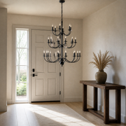 Scale | matte-black 18-light chandelier hanging beside a full-height paneled entry door and sidelight
