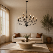 In a room | warm living room with a matte-black 18-light three-tier chandelier above a round travertine table and sofa