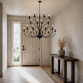 In a room | greige entryway with a matte-black 18-light three-tier chandelier before a paneled door and tall sidelight