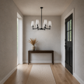 Scale view | matte black six-light chandelier beside an uncropped full-height doorway