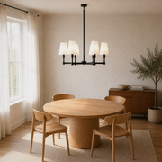 Warm dining room from above | six-light black chandelier over an oak table, window, and olive tree