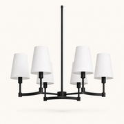 Studio front | six-light chandelier with matte black arms, white fabric drum shades, canopy, and downrod