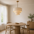 In a room | three-tier oatmeal linen drum chandelier over a round oak dining table